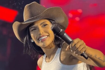 Flay sorrindo, em trecho de show com chapéu no cabeça