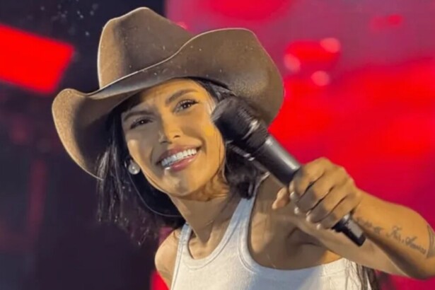 Flay sorrindo, em trecho de show com chapéu no cabeça