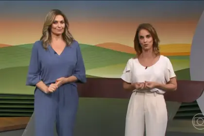 Cristina Vieira veste conjunto azul cinza e Helen Martins um conjunto bege. As duas estão em pé no centro do cenário do Globo Rural