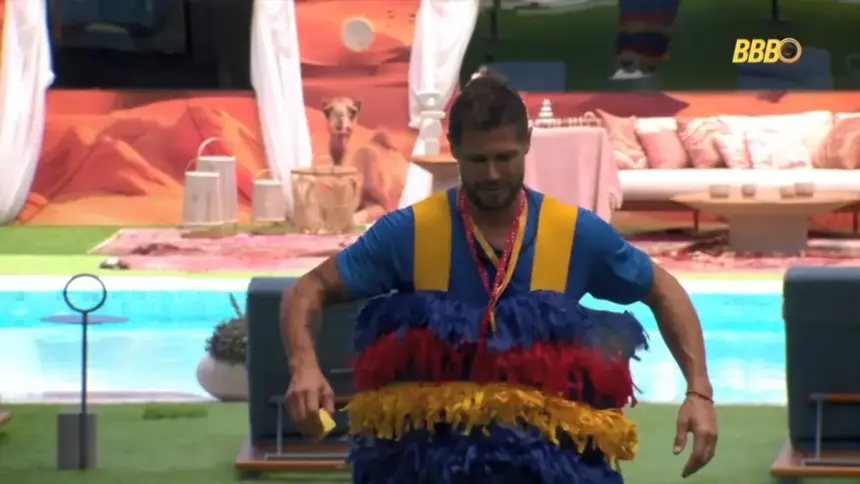 Jonas caminha pelo gramado da área externa do BBB 26 vestido como esponja no Monstro do BBB 26