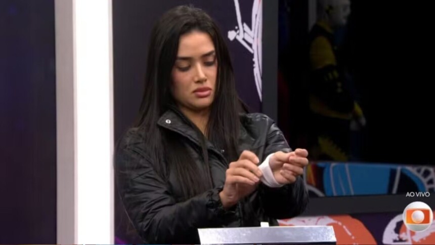 Jordana colocando a pulseira do Paredão após a dinâmica do Triângulo de Risco no BBB 26