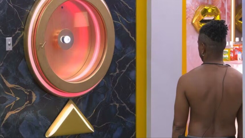 Leandro encarando o Botão de Desistência, que está vermelho, no BBB 26