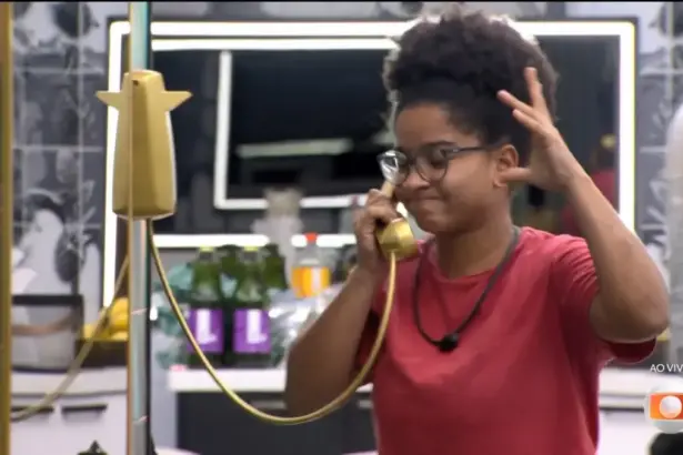 Milena atendeu o Bg Fone dourado da cozinha do BBB 26 e levanta um braço assustada