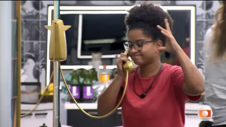 Milena atendeu o Bg Fone dourado da cozinha do BBB 26 e levanta um braço assustada