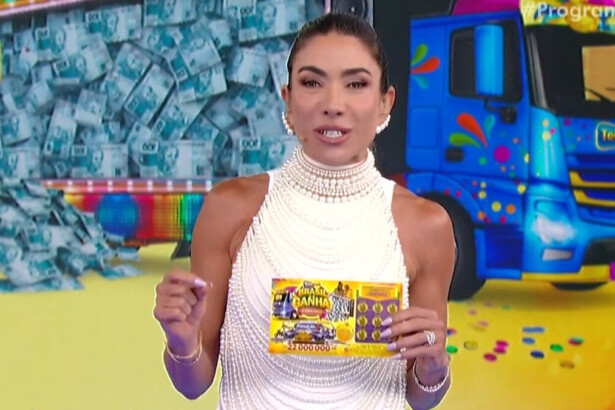 Patricia Abravanel em trecho do quarto sorteio da Tele Sena de Carnaval, segurando uma tele sena e sorrindo