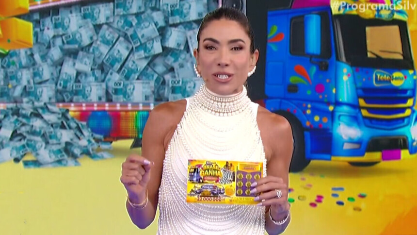 Patricia Abravanel em trecho do quarto sorteio da Tele Sena de Carnaval, segurando uma tele sena e sorrindo