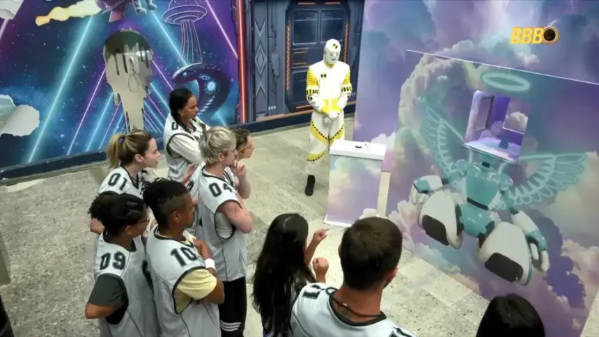 Brothers observam o cenário da Prova do Anjo do bBB 26 com uma cabine com uma torre de latinhas para empilhar