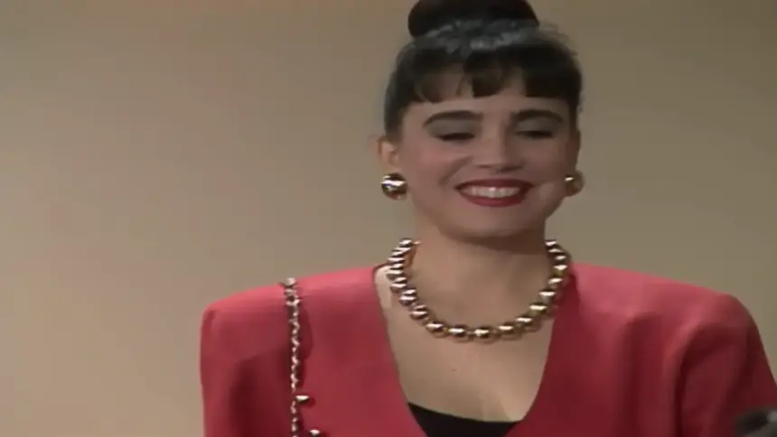 Maria do Carmos sorrindo de vestido e batom vermelhos em cena de Rainha da Sucata