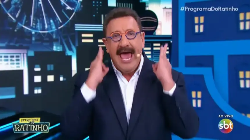 Ratinho com as mãos levantadas e a boca aberta falando contra Erika Hilton no cenário do Programa do Ratinho no SBT