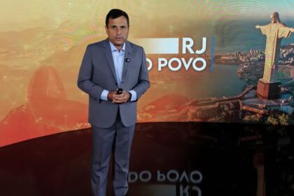 Fabio Barretto de terno cinza na frente do telão cenário do RJ do Povo na RedeTV!