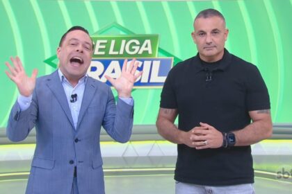 Thiago Gardinalli levanta as mãos para o alto e abre a boca comemorando a audiência ao lado do Delegado Palumbo no cenário do Se Liga Brasil
