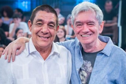Serginho Groisman e Zeca Pagodinho abraçados e sorrindo no palco do Altas Horas