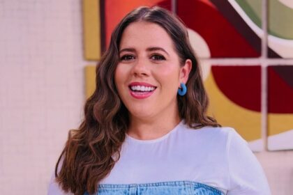 Tati Machado sorrindo em pé no cenário do Mais VocÊ