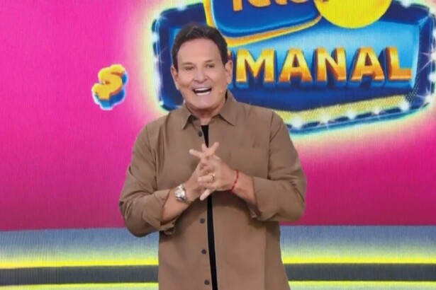 Luis Ricardo com as mãos unidas e sorridente em frente ao telão com o bilhete da Tele sena Semanal rosa edição 96