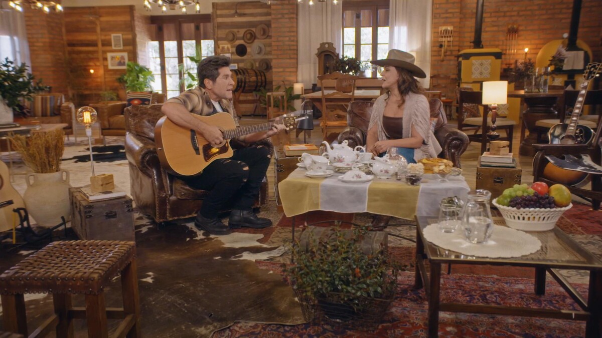 Daniel toca violão enquanto Sula Miranda canta, sentados na sala de uma fazenda no Viver Sertanejo