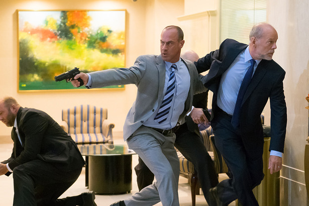 Homem usando terno corre enquanto atira em cena do filme Assalto Ao Poder