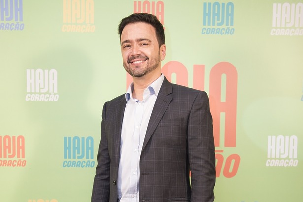 Daniel Ortiz autor da TV Globo de terno cinza em frente ao painel da estreia da novela Haja Coração