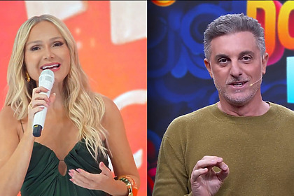 Eliana segura microfone branco no cenário do Em Família com Eliana dividindo tela com Luciano Huck no Domingão