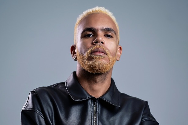 Hiran com casaco preto e olha sério em divulgação do novo álbum Imundo