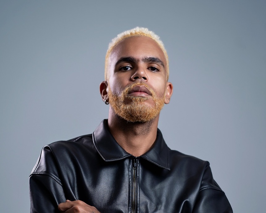 Hiran com casaco preto e olha sério em divulgação do novo álbum Imundo