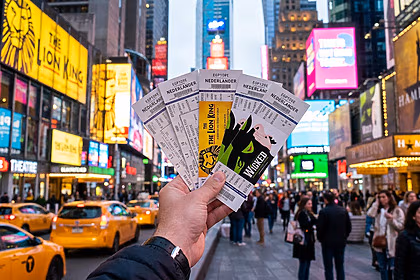 Mão segura ingressos de musicais da Broadway comprados no Hellotickets na avenida de Nova York