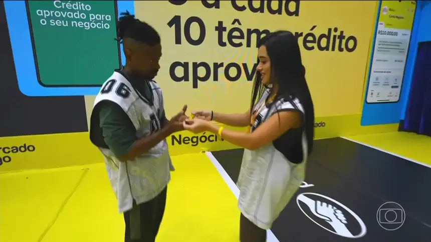 Jordana entrega pulseira para Leandro Boneco que olha para ela assustado no cenário da Prova do Líder do BBB 26