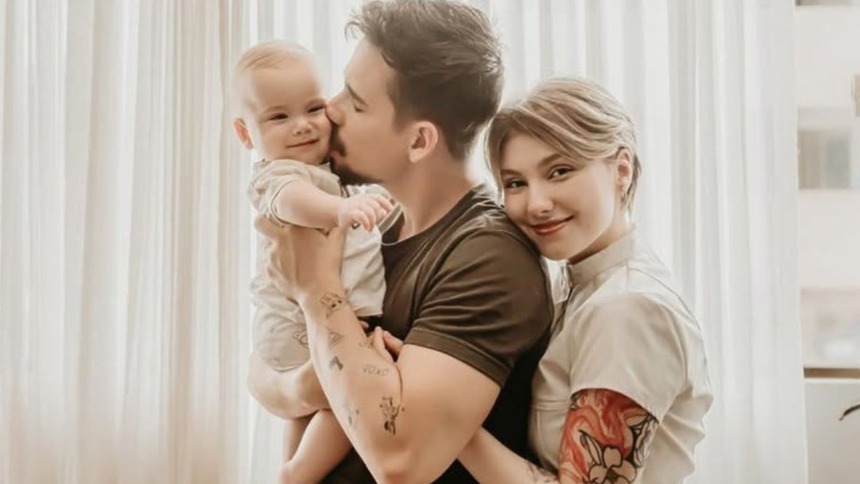 Lucas Borbas e Isabel Veloso, com o filho colo, sorrindo em momento de família