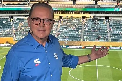 Luis Roberto apontando para um estádio no fundo
