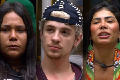 Chaiany, Juliano e Marciele, com expressões sérias, sentam-se no sofá do BBB 26 após descobrirem que estão no 13º Paredão