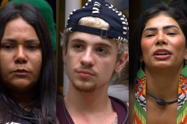 Chaiany, Juliano e Marciele, com expressões sérias, sentam-se no sofá do BBB 26 após descobrirem que estão no 13º Paredão