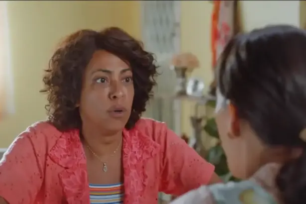 Protagonista do filme Não Vamos Pagar nada, sentada na mesa de uma cozinha simples em uma casa antiga, olhando para sua amiga