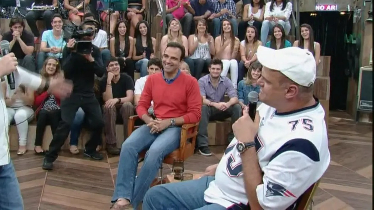 Tadeu Schmidt sorrir ao lado de Oscar Schmidt no palco do Altas Horas