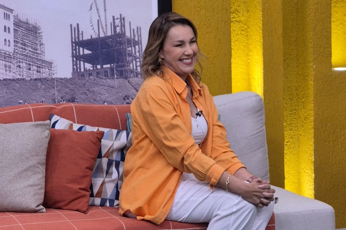 Paula Guimarães sentada no sofá do  Família dos Devotos na TV Aparecida