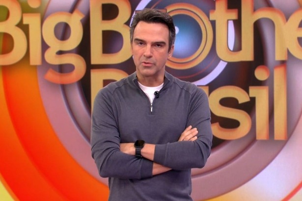 Tadeu Schmidt de braços cruzados no cenário do BBB 26
