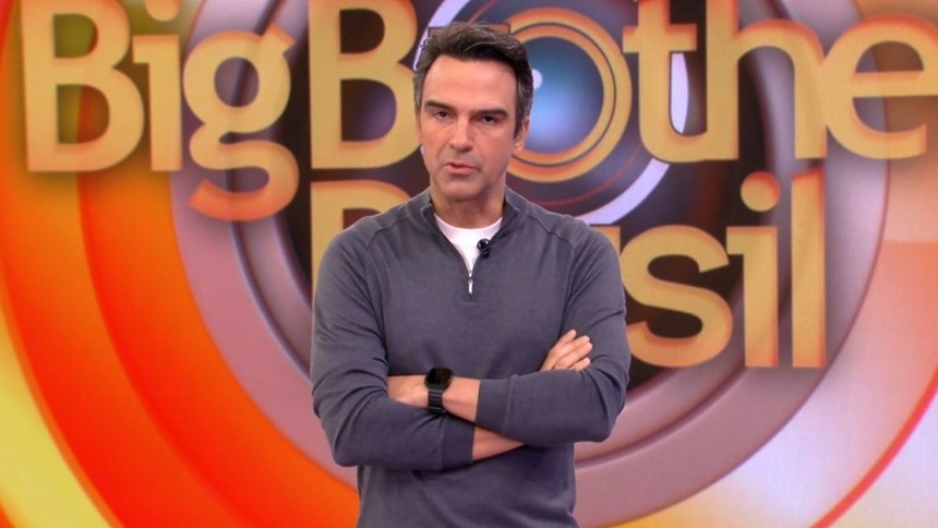 Tadeu Schmidt de braços cruzados no cenário do BBB 26