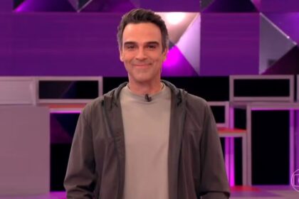 Tadeu Schmidt, sorriden no cenário do BBB 26, explicando a dinâmica da semana