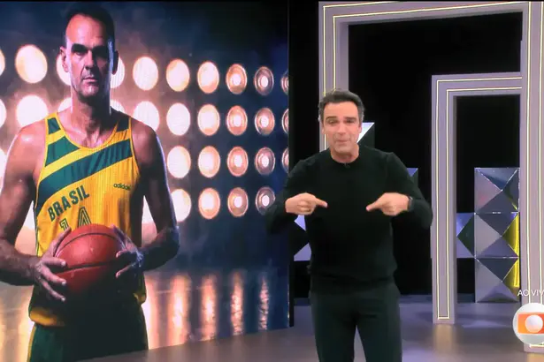 Oscar Schmidt no telão do BBB 26 segurando bola de basquete enquanto Tadeu Schmidt chora em frente ao telão