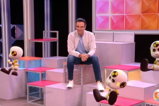 Tadeu Schmidt sentado no cenário do BBB 26