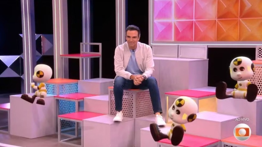 Tadeu Schmidt sentado no cenário do BBB 26
