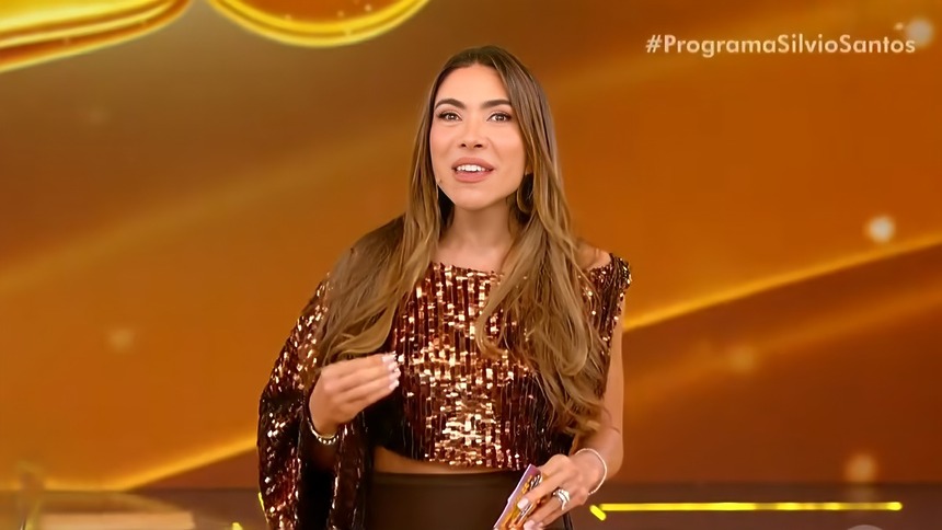 Patricia Poeta sorridente segurando bilhete da Tele Sena de Páscoa 2026 no palco do Programa Silvio Santos