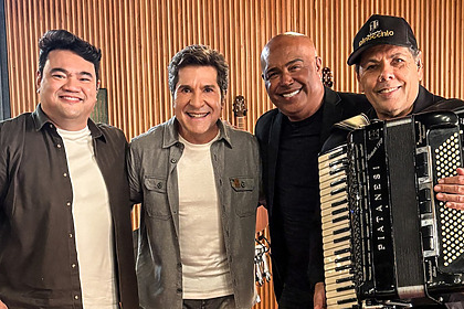 Daniel abraça Maestro Pinocchio, Ivan Miyazato e Rick Sollo. Todos estão em pé e sorridentes no centro do cenário do Viver Sertanejo