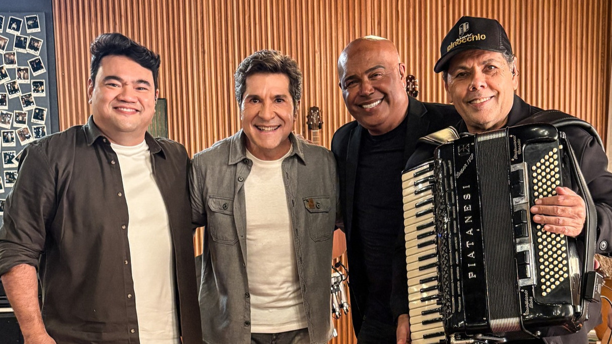 Daniel abraça Maestro Pinocchio, Ivan Miyazato e Rick Sollo. Todos estão em pé e sorridentes no centro do cenário do Viver Sertanejo