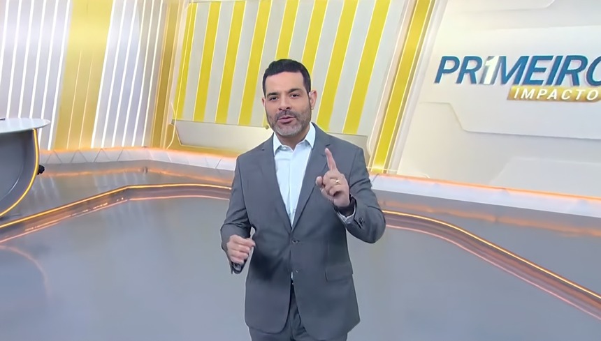 Darlisson Dutra levanta o dedo apontando para o alto no cenário do Primeiro Impacto