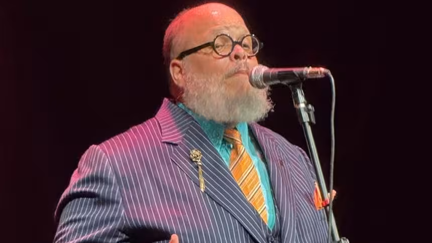 Ed Motta de terno cantando em um show