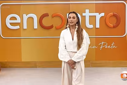 Patrícia Poeta em frente ao telão com o novo logo do programa Encontro que agora predomina os tons de amarelo e salmon