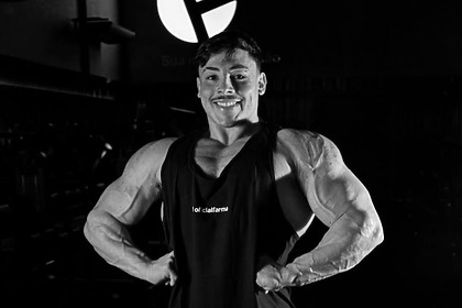 Gabriel Ganley fazendo pose para exibir o corpo musculoso em uma academia. A Imagem está em preto e branco representando o luto