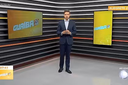 Leonardo Lara apresentando o Guaíba no Ar. Ele está de terno preto no novo cenário da RECORD Guaíba que tem piso branco, paredes em tons escuros, com linhas de LED amarelo e laranja
