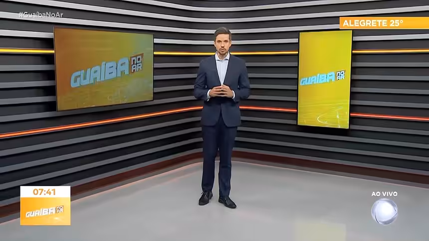 Leonardo Lara apresentando o Guaíba no Ar. Ele está de terno preto no novo cenário da RECORD Guaíba que tem piso branco, paredes em tons escuros, com linhas de LED amarelo e laranja