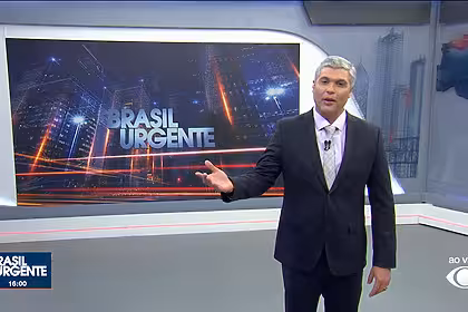 Joel Datena em pé no centro do cenário do Brasil Urgente