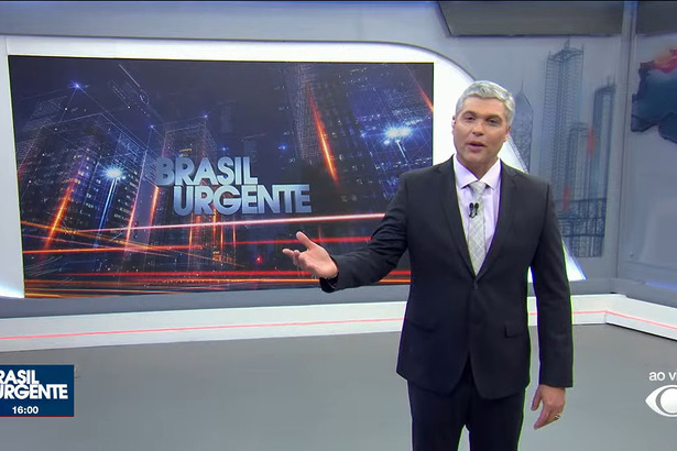 Joel Datena em pé no centro do cenário do Brasil Urgente